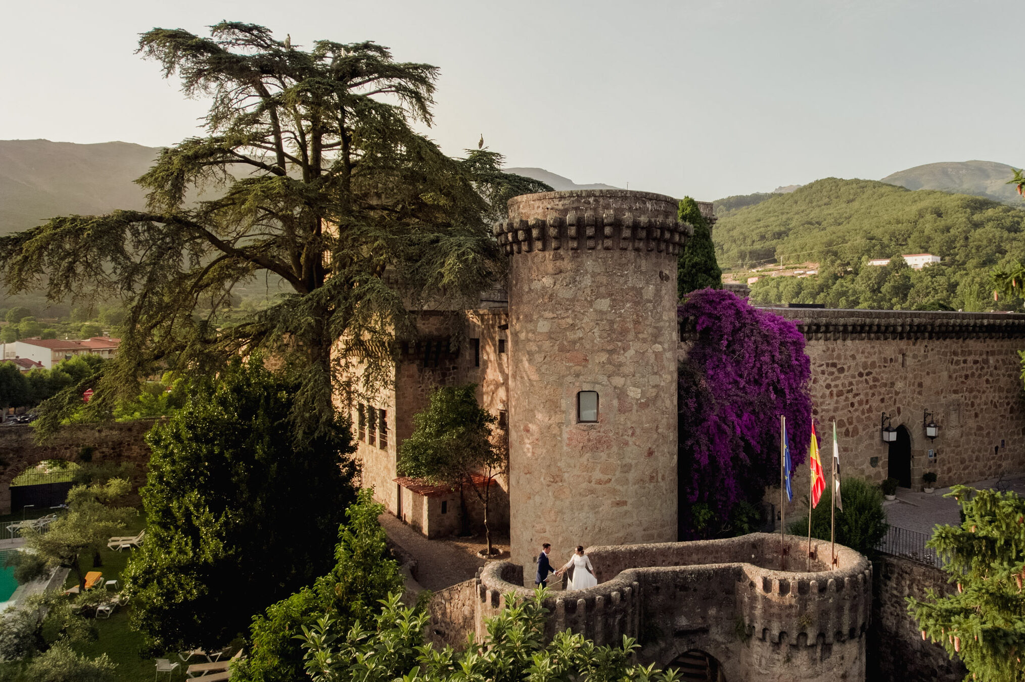 Desde el cielo, la vista aérea captura la imagen encantadora de Belén y Luisma bailando en las torres del Parador de Jarandilla. Fotógrafos de bodas en Extremadura. Boda en el Parador de Jarandilla de la Vera