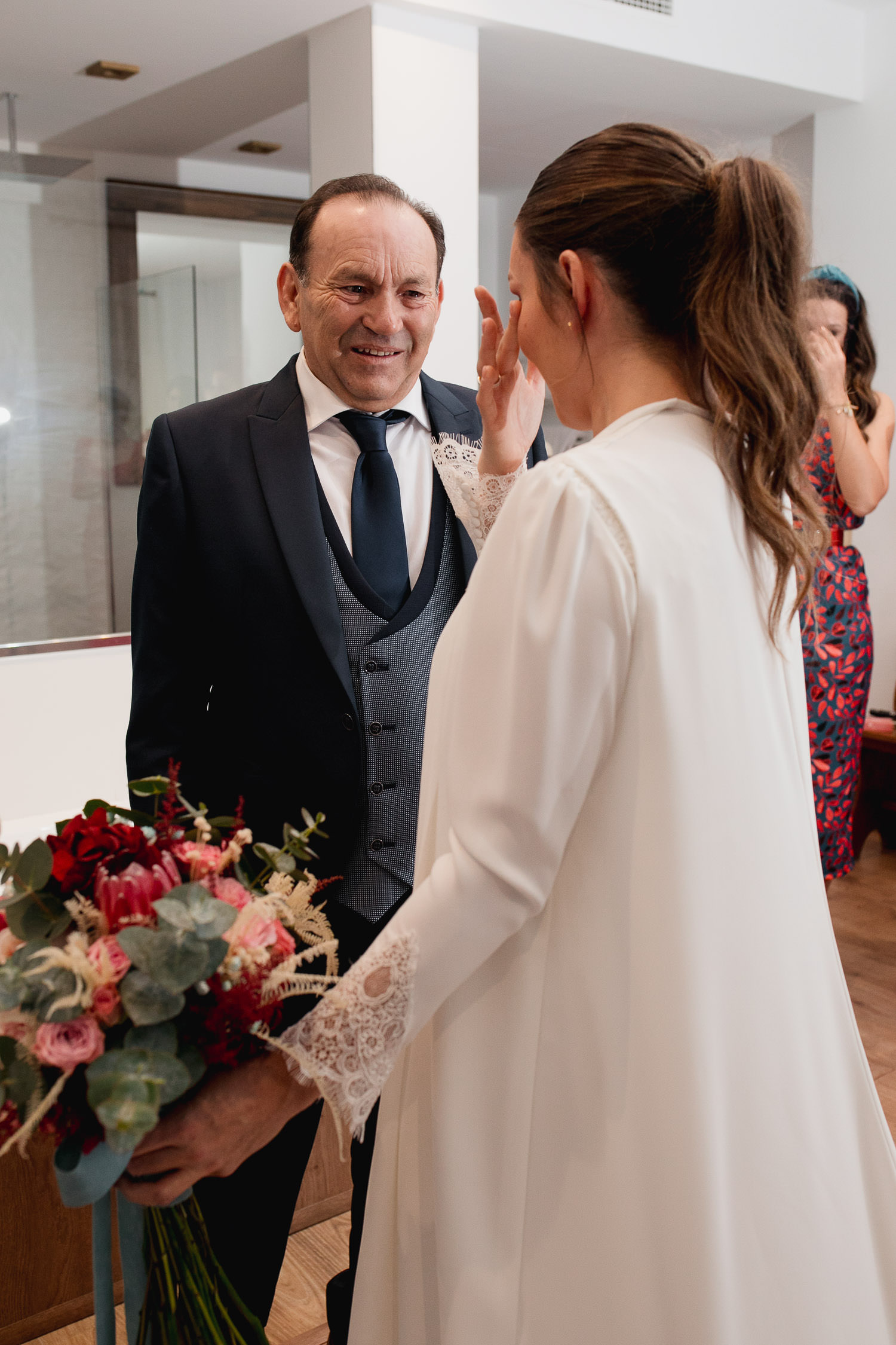 La novia se emociona al ver a su padre recién vestida de novia, mostrando una sonrisa brillante y lágrimas de felicidad mientras se miran en un momento conmovedor antes de la ceremonia.