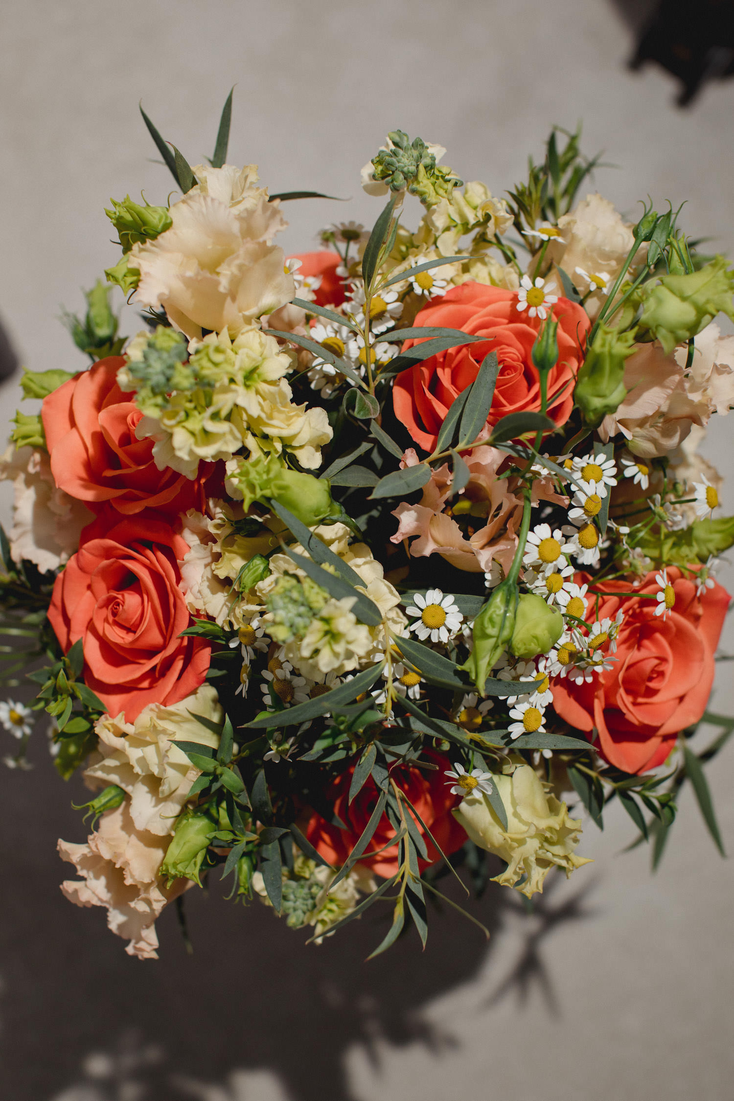 boda de otoño en el Castillo de la Arguijuela 1 Vista superior del ramo de novia con flores silvestres en tonos naranja, crema y verde, con margaritas pequeñas.