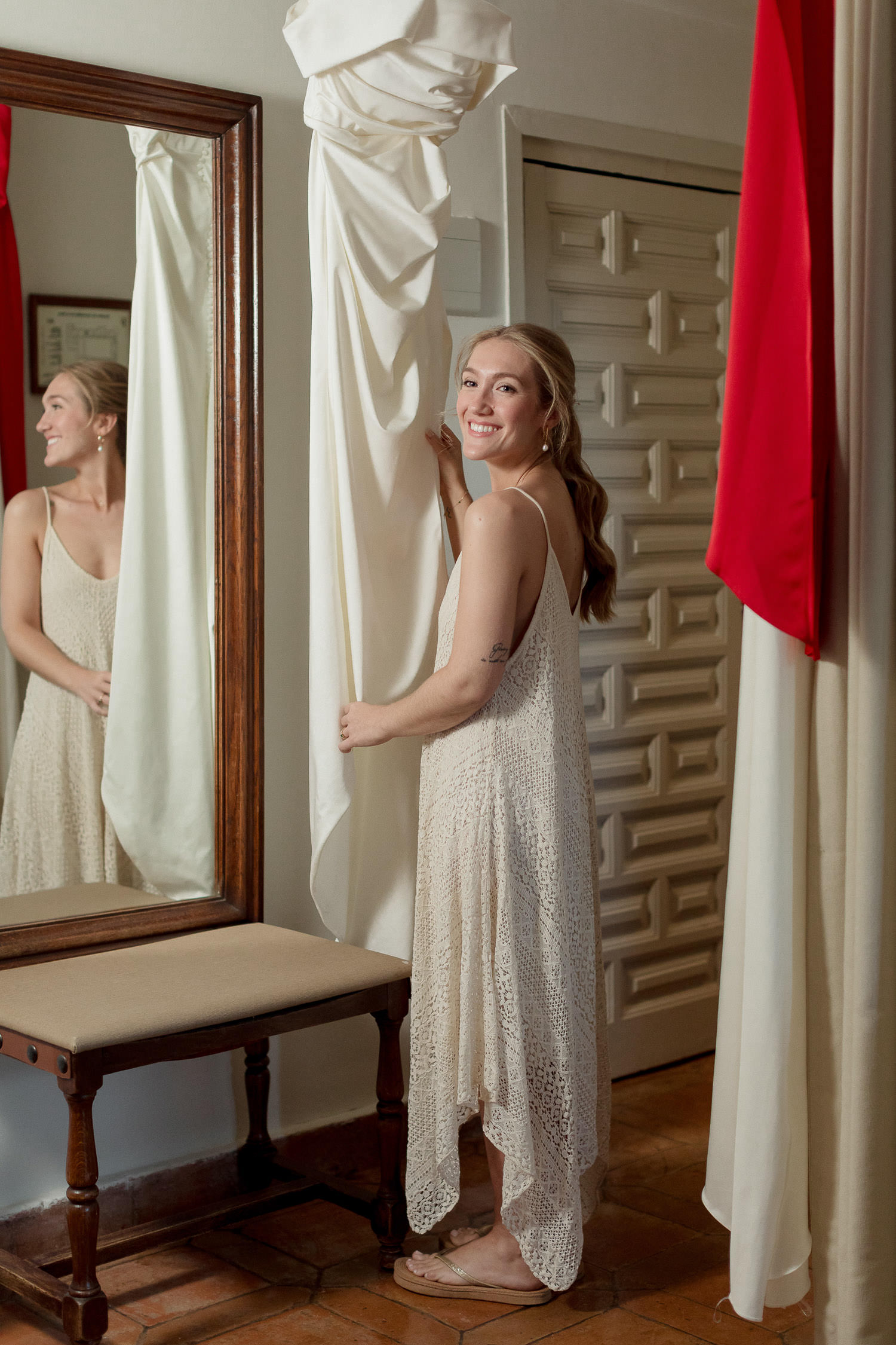 Una boda civil en el Parador de Jarandilla 11 Primer plano de la novia sonriendo con dulzura mientras contempla el vestido de boda, reflejando la felicidad y la emoción del momento.