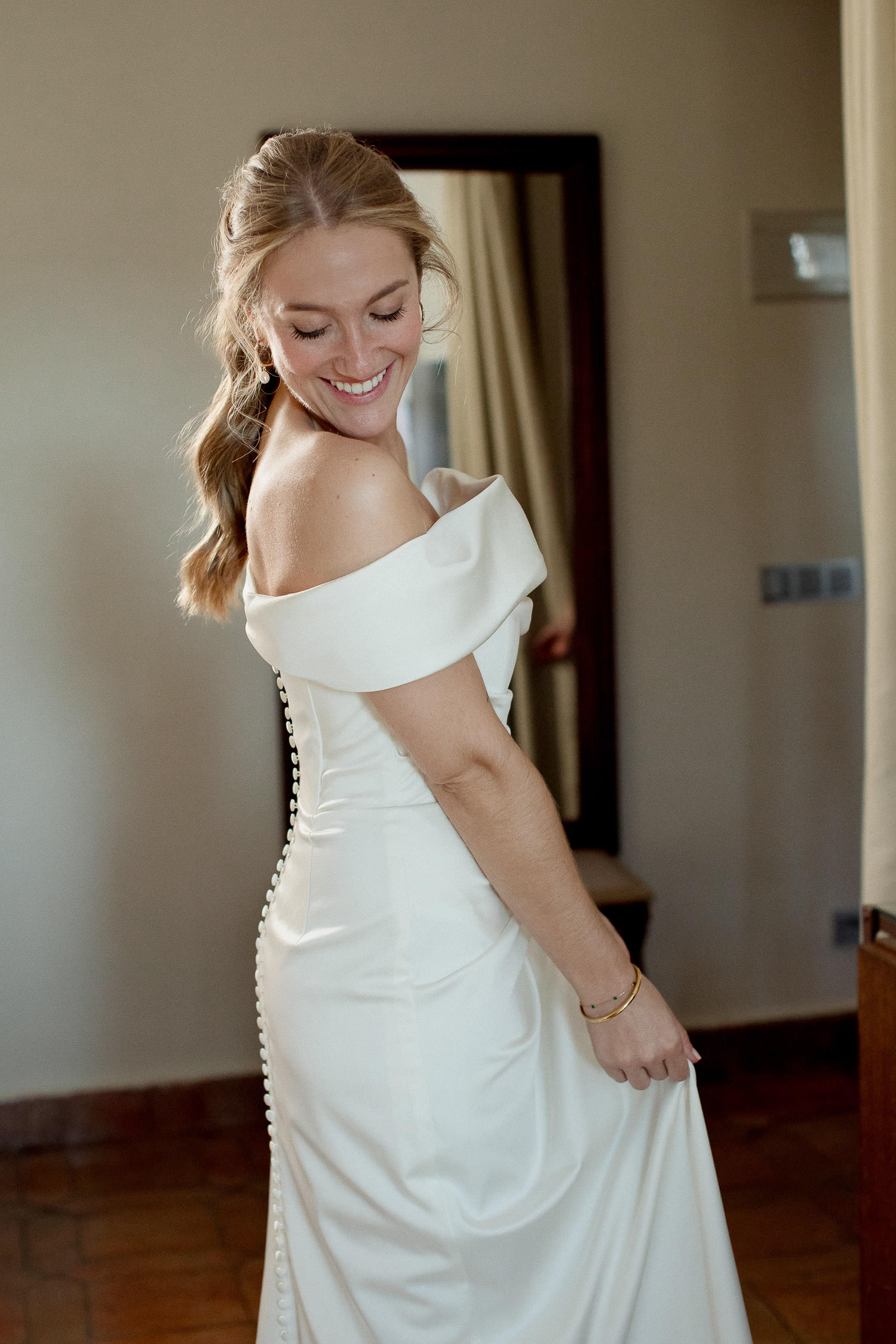 Una boda civil en el Parador de Jarandilla 18 Detalle de la caída del vestido con los botones forrados en la espalda, mientras la novia sonríe con ternura.
