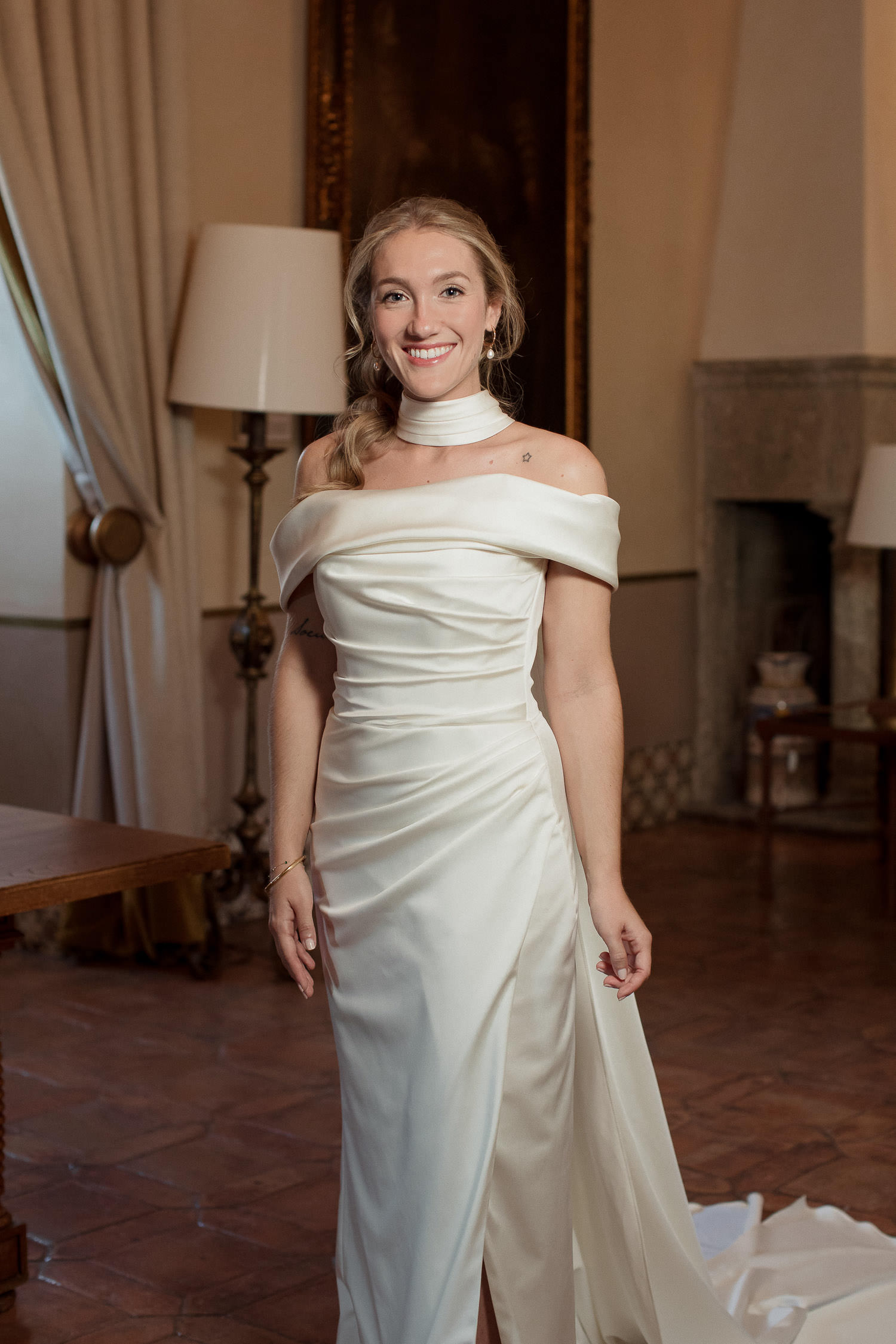 Una boda civil en el Parador de Jarandilla 20 Primer plano de la novia sonriendo hacia la cámara, con la decoración del parador en el fondo y su peinado romántico resaltando su look.