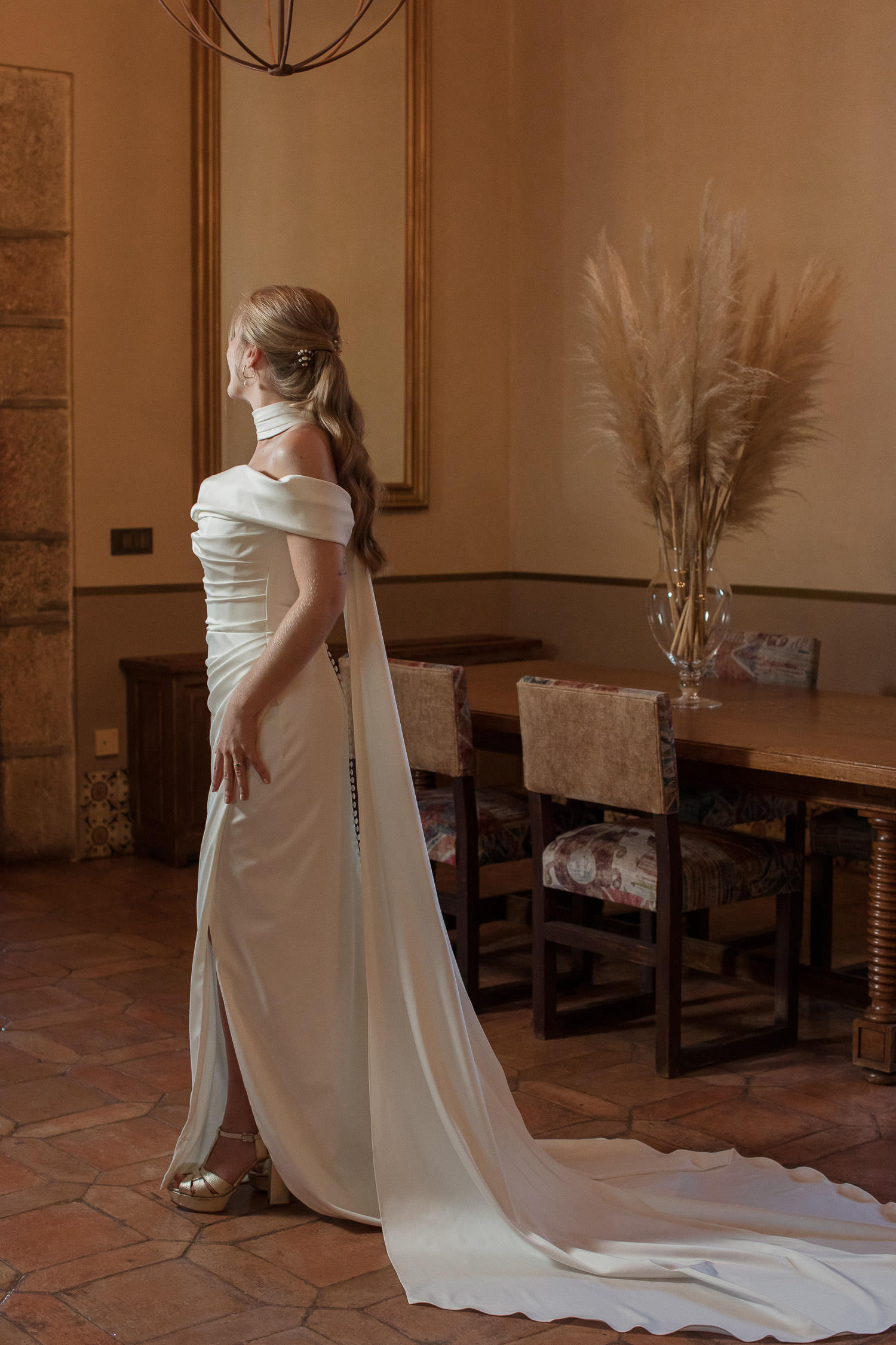 Una boda civil en el Parador de Jarandilla 23 La novia luce su elegante vestido blanco con una capa larga que realza su silueta, capturando un momento de serenidad y belleza antes de la boda civil en el Parador de Jarandilla de la Vera.