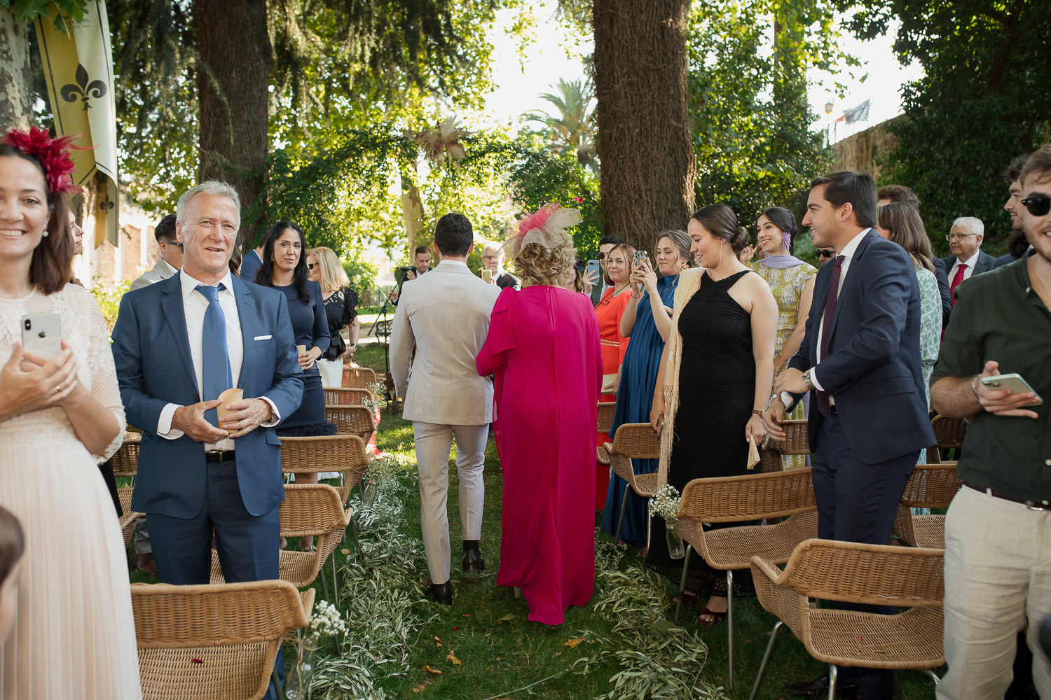 Una boda civil en el Parador de Jarandilla 31 Invitados de pie, algunos con móviles, mirando con cariño la llegada del novio y su madre al lugar de la ceremonia.